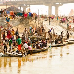 Colorful gathering at Prayagraj with boats and pilgrims on the Ganges riverbank.