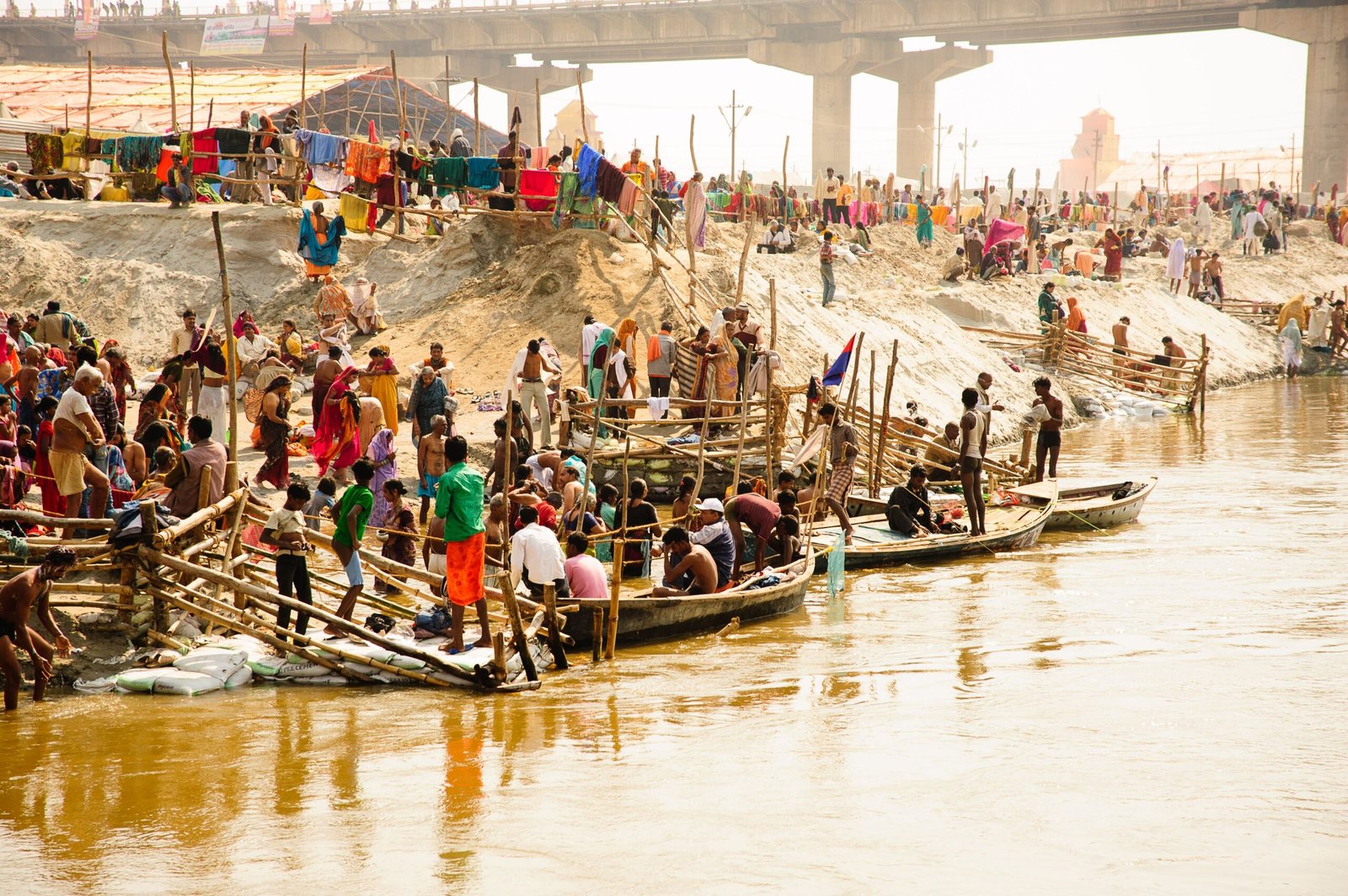 Colorful gathering at Prayagraj with boats and pilgrims on the Ganges riverbank.